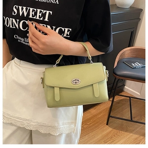 Detalle de bolso bandolera de cuero verde claro con cierre giratorio plateado y asa única