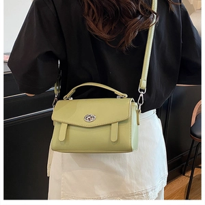 Vista posterior de un bolso mensajero verde salvia con cierre plateado en una modelo