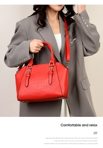 Detail of red crocodile pattern shell bag with buckle straps and shoulder strap