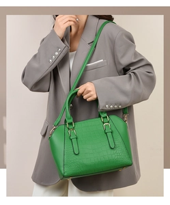 Model wearing a green crocodile embossed shell bag with a detachable shoulder strap