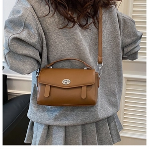 Bolso bandolera marrón con cierre de metal giratorio llevado por una modelo