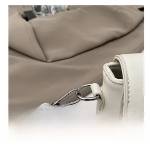 Detalle del gancho de metal plateado y las costuras del bolso bandolera de cuero blanco