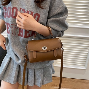 Bolso bandolera rectangular marrón con cierre plateado y asa superior mostrado en modelo