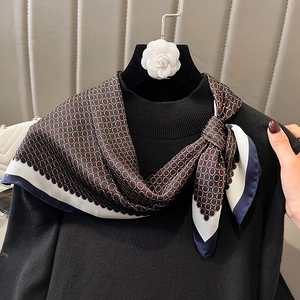 Close-up of silk scarf with red and black geometric rings tied over a black sweater