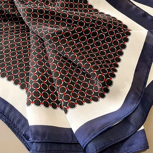 Macro shot of silk-like scarf featuring black polka dots and elegant contrast borders