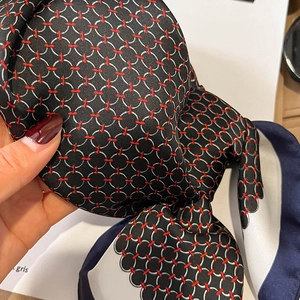 Close-up of a silk scarf featuring a black chain-link pattern and deep blue borders