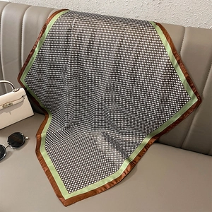 Detail of geometric dot pattern silk scarf with green border on leather background