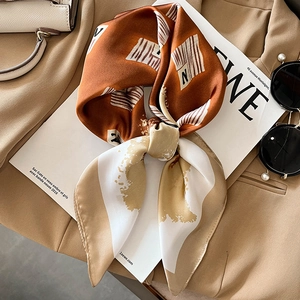 Silk-like fashion scarf with orange newspaper print and letter N on beige background