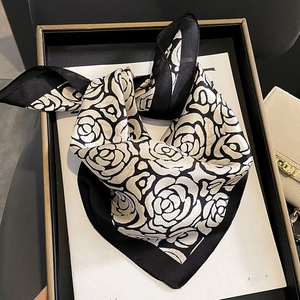 Elegante sciarpa in seta a camelia bianca e nera da donna su un vassoio regalo di lusso