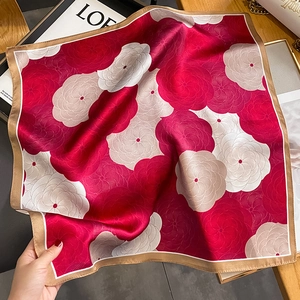 Élégant carré en soie au motif floral en spirale rouge drapé sur une table en bois