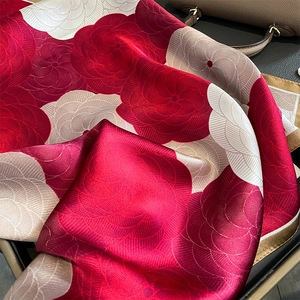 Élégant foulard en soie à imprimé floral rouge et crème drapé sur fond de cuir