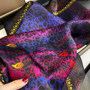 Elegant mulberry silk scarf with vibrant paisley and leopard print patterns in deep blue