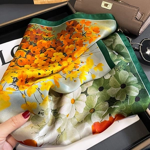 Fashionable floral silk scarf with orange patterns and dark green border on tray