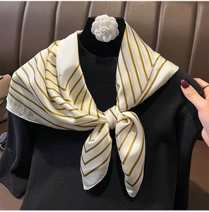 Detail of striped silk scarf with gold accents and decorative camellia flower detail