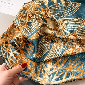 Detailed view of dark green and orange silk scarf with abstract leaf vein pattern texture