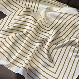 Close-up of striped silk scarf with golden lines and glossy satin texture