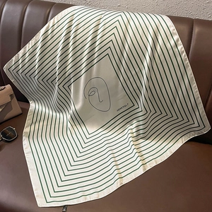 Detail of artistic striped silk scarf with HEARTFELT text on a brown leather sofa