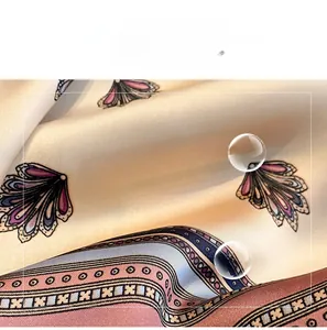 Close-up of soft faux silk scarf featuring purple scallop patterns and beige base