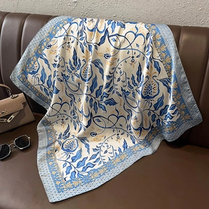 Dettaglio di un foulard di seta vintage blu e oro drappeggiato su un divano in pelle