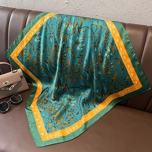 Dettaglio di un foulard in seta vintage a fiori su un divano in pelle con accessori