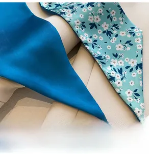Gros plan détaillé de foulards étroits en soie bleu marine et à fleurs sur beige