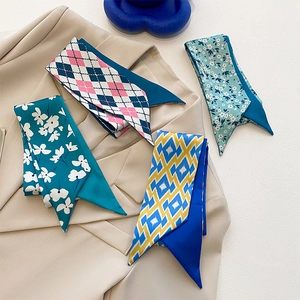 Détail de quatre foulards twilly à motifs stylisés sur une veste de blazer beige
