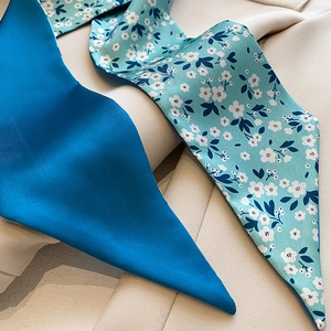 Gros plan détaillé d'un foulard en soie à fleurs bleues sur un blazer blanc, texture soyeuse