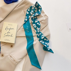 Vue détaillée d'une écharpe élégante en soie bleue fleurie portée avec un blazer beige