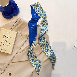 Détail d'un foulard en soie bleu et jaune à motif géométrique sur un blazer
