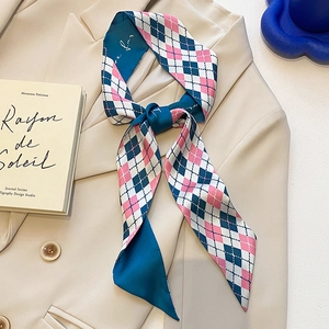 Élégant foulard étroit en soie à losanges noué sur le col d'un blazer beige chic