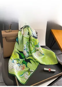 Détail d'un foulard en soie à imprimé floral vert drapé sur un sac à main de luxe raffiné