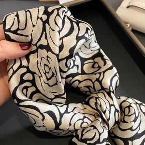 Macro shot of camellia silk scarf showing smooth satin texture and elegant drape