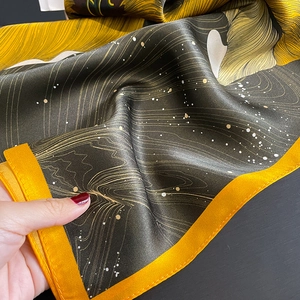 Detail of silk scarf showing vibrant sunflower print and orange rolled edge texture