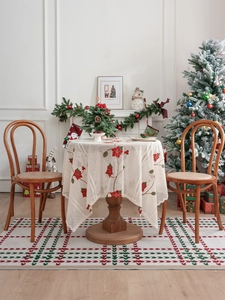 Dettaglio del ricamo di poinsettia rossa su tovaglia natalizia in pizzo beige raffinato