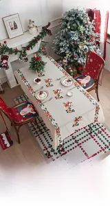 Close-up of embroidered Christmas tablecloth with Santa, reindeer and vine motifs