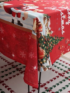 Detail of red Christmas tablecloth featuring Santa, trees, and woven fabric texture