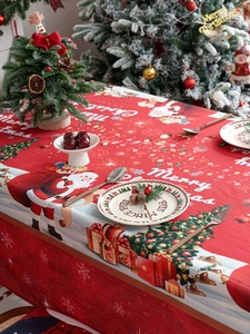 Detailed view of red Christmas tablecloth with Santa Claus and festive prints on a table
