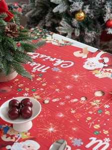 Close-up of red Christmas tablecloth with Santa Claus motifs and festive dining texture