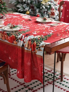 Detail of red Christmas tablecloth featuring Merry Christmas text and festive ornaments