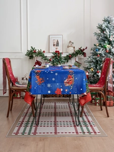 Close-up of blue Christmas tablecloth with Santa and reindeer motifs with red chair covers
