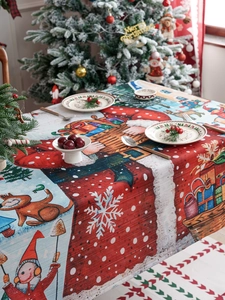 Detail of red Christmas tablecloth featuring Santa, snowmen, and festive winter patterns