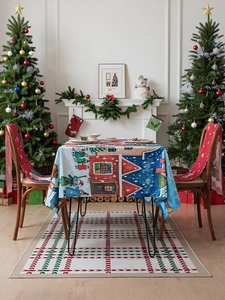 Detailed Christmas table set with snowy cottage scene tablecloth and red chair covers