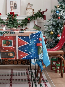 Detailed view of Christmas tablecloth draping with snow-covered house and star patterns