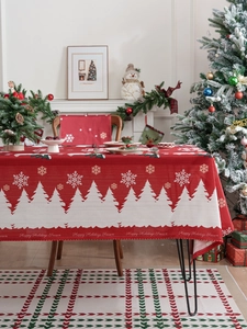 Detail of red Christmas tablecloth with snowy pine forest pattern and festive text