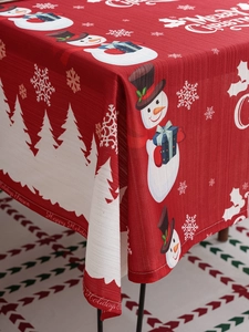 Close-up of red Christmas tablecloth featuring snowmen, snowflakes, and festive typography