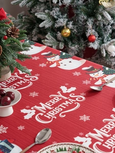 Detail of red Christmas tablecloth with snowman pattern and Merry Christmas text