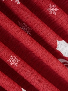 Close-up of red Christmas tablecloth featuring white snowflake patterns and woven texture