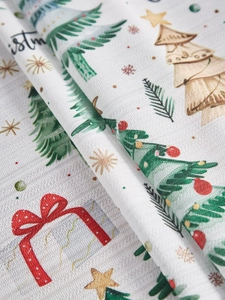 Detailed close-up of Christmas tablecloth fabric with festive tree and gift box patterns