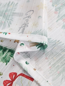 Close-up of translucent Christmas tablecloth featuring festive trees and gift patterns