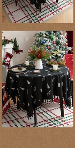 Macro detail of black Christmas tablecloth with white reindeer embroidery and tassel fringe